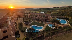 A resort with multiple swimming pools, a large building, and a sunset view.