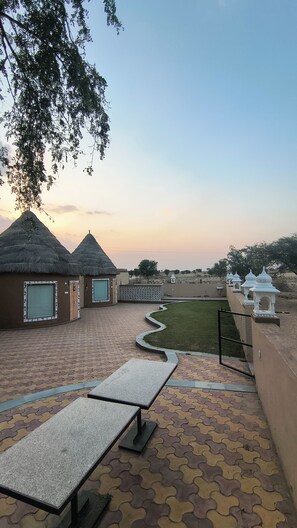 Un patio con cabañas de techo de paja, un camino empedrado y una vista del horizonte.