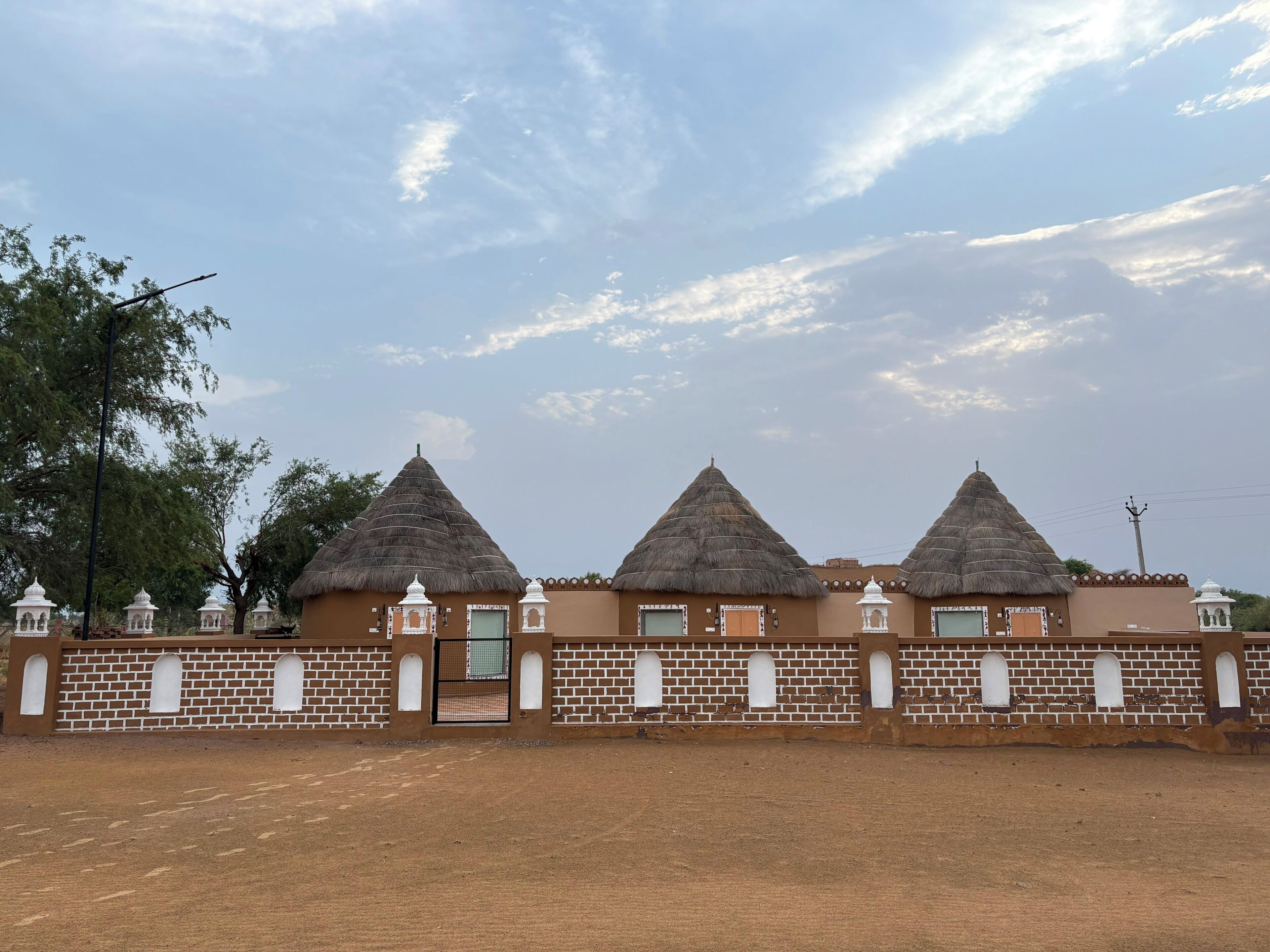 A row of thatched-roof buildings with brick walls and white window frames.