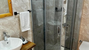 A modern bathroom with a glass-enclosed shower, a sink, and a toilet. - İda Lythos (Ayvacik)