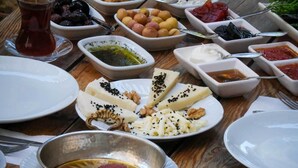 A table with various dishes including bread, olives, and dips. - İda Lythos (Ayvacik)