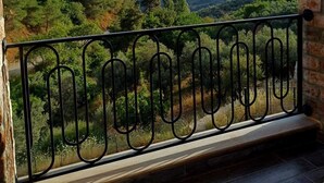 A balcony with a metal railing overlooking a mountainous landscape with trees and hills. - İda Lythos (Ayvacik)