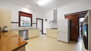 A modern kitchen with white cabinets, a stainless steel range hood, and a built-in dishwasher. - Beautifully restored 1930s gem, perfectly located in the heart of Portland. (Glenelg)