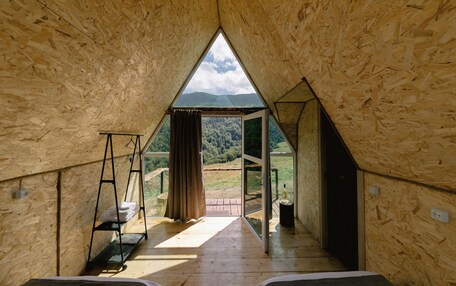 A triangular wooden room with a view of a forested landscape.