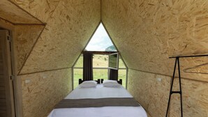 A triangular room with a bed, a ladder, and a view of the outdoors. - OKON Highlands Cottages & Camp (Yenokavan)