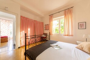 A bedroom with a bed, a desk, a chair, and a window with curtains. - Monterosso Apartments (Monterosso al Mare)