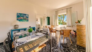 A dining area with a glass table, chairs, and a sofa in a bright room with a view. - Monterosso Apartments (Monterosso al Mare)