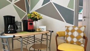 A small kitchenette with a coffee maker, a vase with yellow flowers, and a mug on the counter.