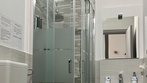 A modern bathroom with a glass-enclosed shower, a toilet, a sink, and a cabinet.