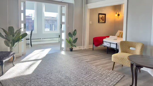 A spacious living area with a large window, a ceiling fan, and a cozy seating arrangement. - Spacious & Convenient near NYC (West New York)