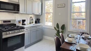 A modern kitchen with grey cabinets, a black stove, and a large window. - Spacious & Convenient near NYC (West New York)