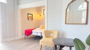 A bedroom with a bed, a chair, a table, and a mirror. - Spacious & Convenient near NYC (West New York)
