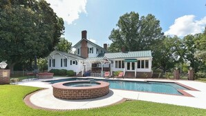 A house with a swimming pool, a covered patio, and a brick fire pit.