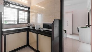 Eine moderne Küche mit schwarzem Arbeitsplatz, einer Mikrowelle und einem Toaster. Ein Fenster mit Jalousien, ein Schrank und eine Tür zu einem anderen Raum sind ebenfalls vorhanden.