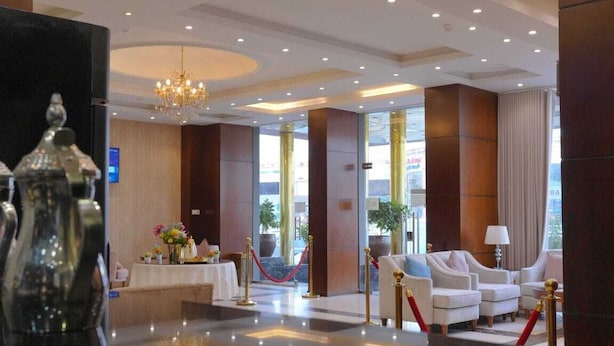 Eine Hotelhalle mit Empfangstresen, Sitzgelegenheiten und großen Fenstern.