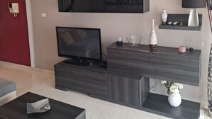 A modern living room with a flat-screen TV, dark wood furniture, a red accent wall, and a minimalist decor style. - Mogan Playa 19 by El Sirocco (Lomo Quiebre)