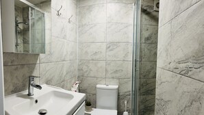 A bathroom with a white sink, toilet, and glass shower enclosure. - Brighton charm – Near Beach, City Centre & Station (Brighton and Hove)