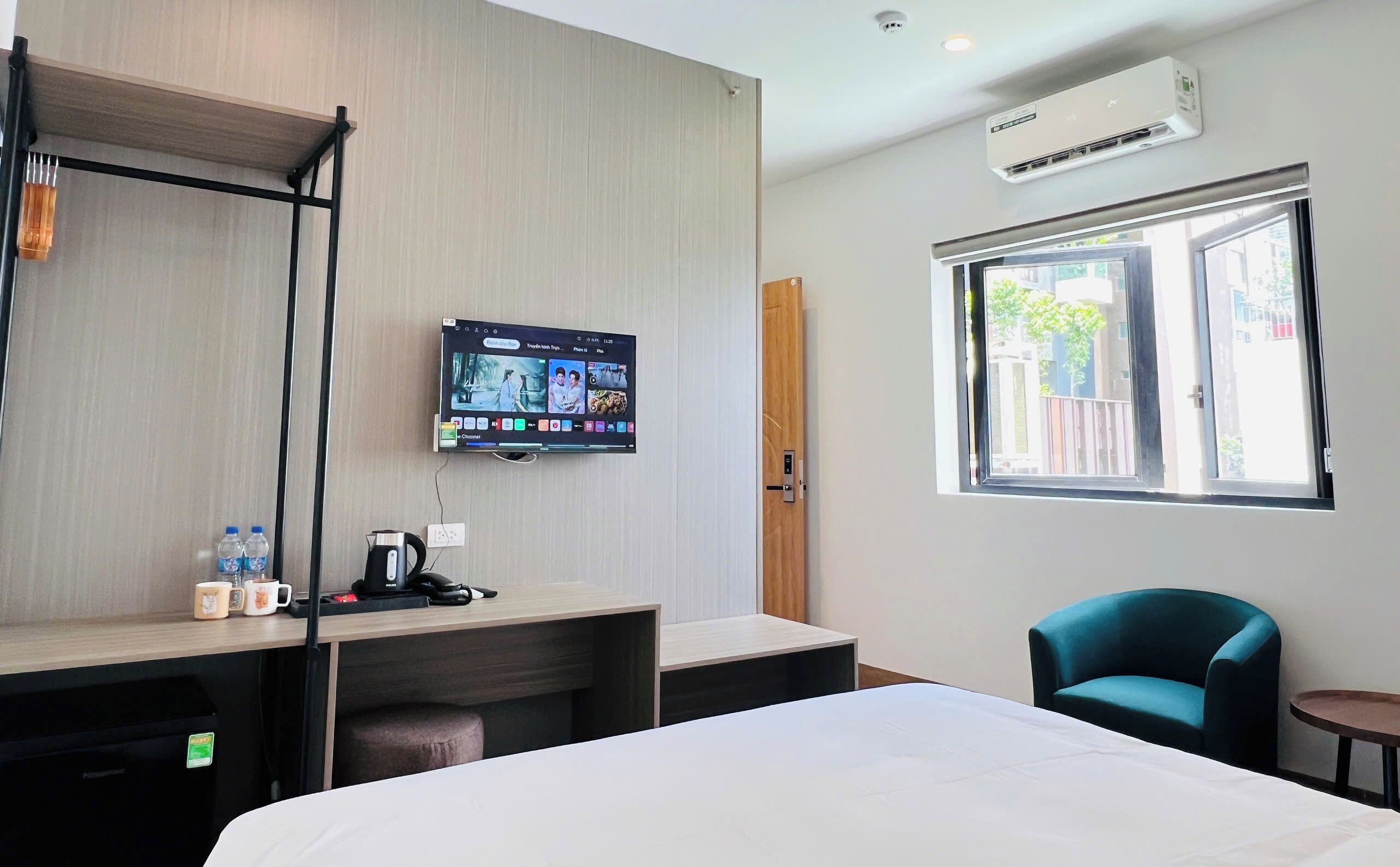 Une chambre d’hôtel avec un lit, un bureau avec un ordinateur, une télévision, une fenêtre et une chaise.