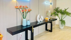A reception desk with a black surface, two vases with flowers, a water dispenser, and a potted plant.