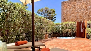 A sunlit outdoor area with a hot tub, lounge chairs, and a stone wall. - Ferienhaus 4 Personen in Son Moja Santanyí, 900 m von der Cala Santanyí (Santanyi)
