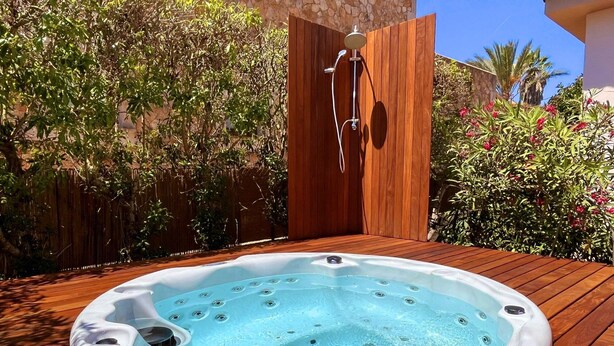 A hot tub on a wooden deck with a stone wall and plants in the background. - Ferienhaus 4 Personen in Son Moja Santanyí, 900 m von der Cala Santanyí (Santanyi)