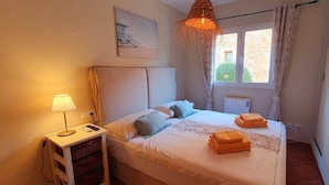 A bedroom with a bed, bedside table, lamp, and a view of the outside. - Ferienhaus 4 Personen in Son Moja Santanyí, 900 m von der Cala Santanyí (Santanyi)