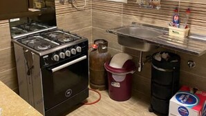 A compact kitchen with a gas stove, oven, and a water heater. - Cozy Modern Apartment in El Rehab 2, (Cairo Governorate)