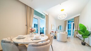 A modern dining area with a round table, chairs, and a vase of flowers. - 1BR Home – Luxury & Comfort Combined (Dubai)