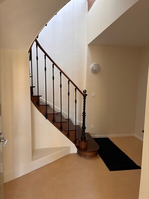 A curved staircase with wooden steps and black balusters, leading to an upper floor.