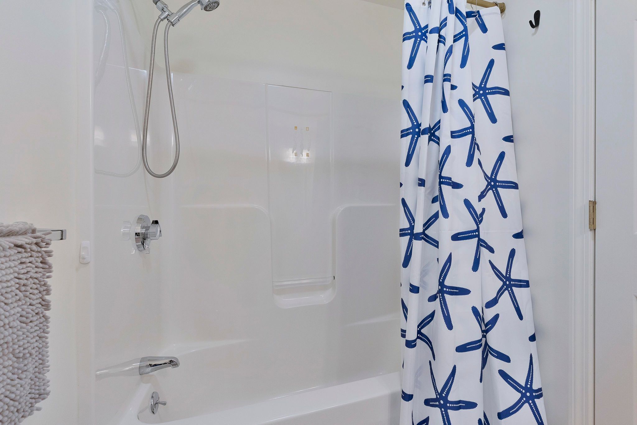Un bagno con vasca, doccia e tenda da doccia a motivo di stella marina.