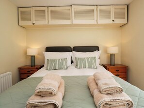 Ein Hotelzimmer mit einem Bett, zwei Nachttischen, zwei Lampen, einem Heizkörper und einem Fenster mit Jalousien.