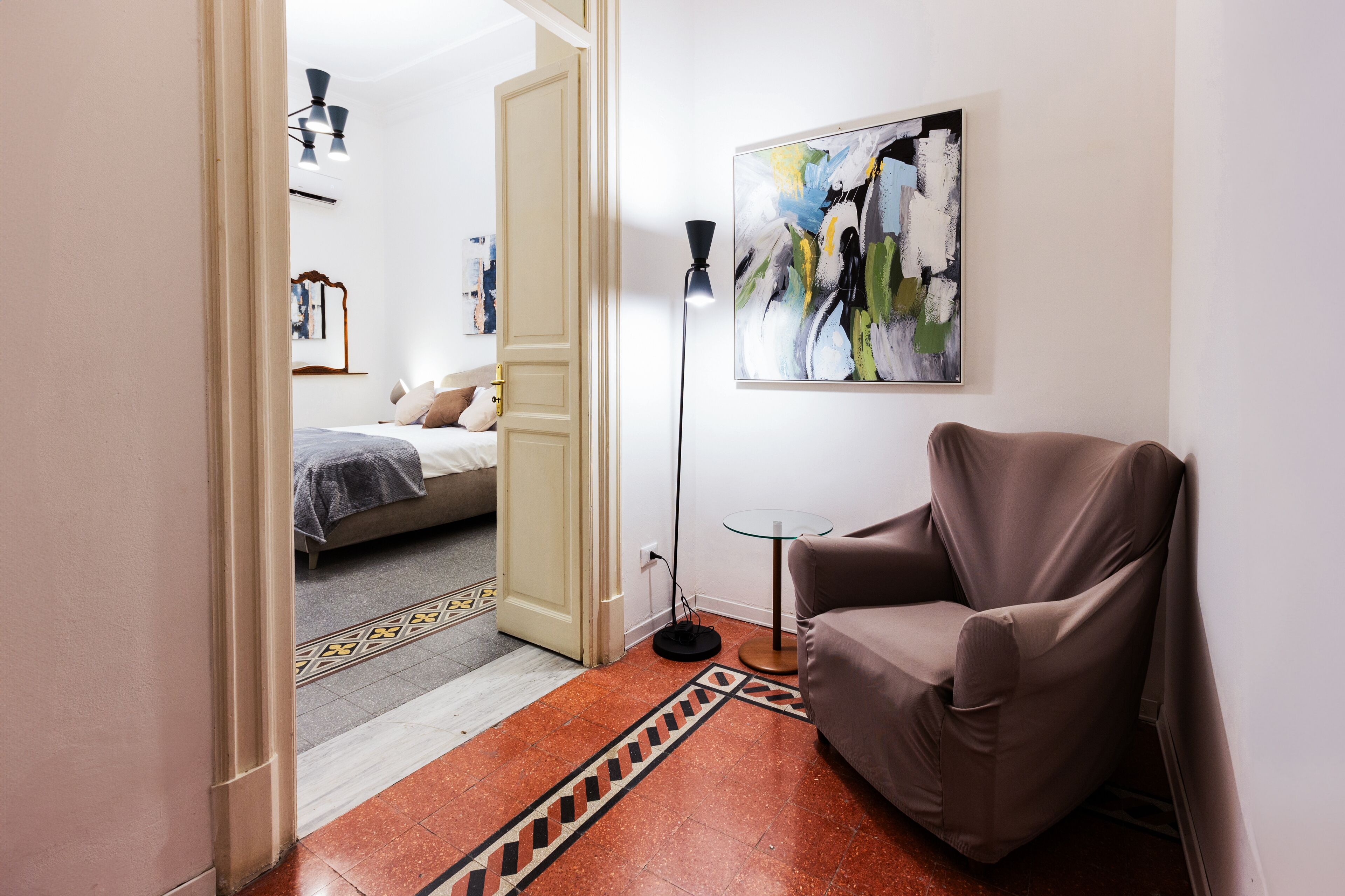 A modern living room with a brown armchair, a floor lamp, and a painting on the wall.