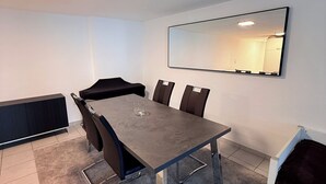 Een vergaderruimte met een rechthoekige tafel, zes stoelen, een grote spiegel aan de muur en een plafondlamp.