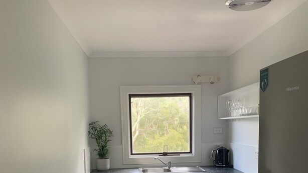Una cocina compacta con armarios blancos, una ventana, un fregadero, una estufa y un refrigerador.