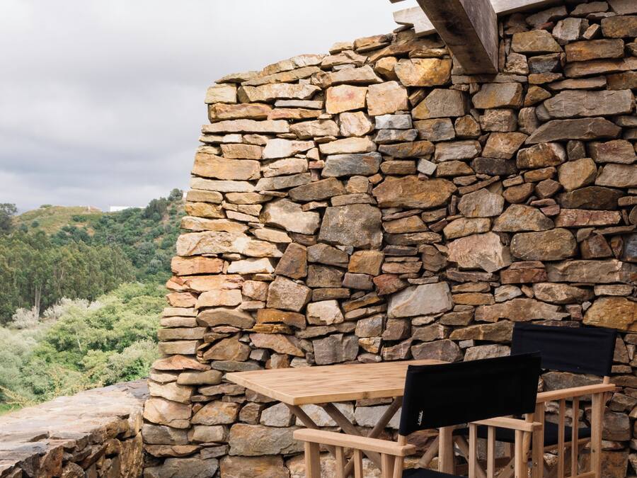 A stone wall with a wooden pergola overhead.