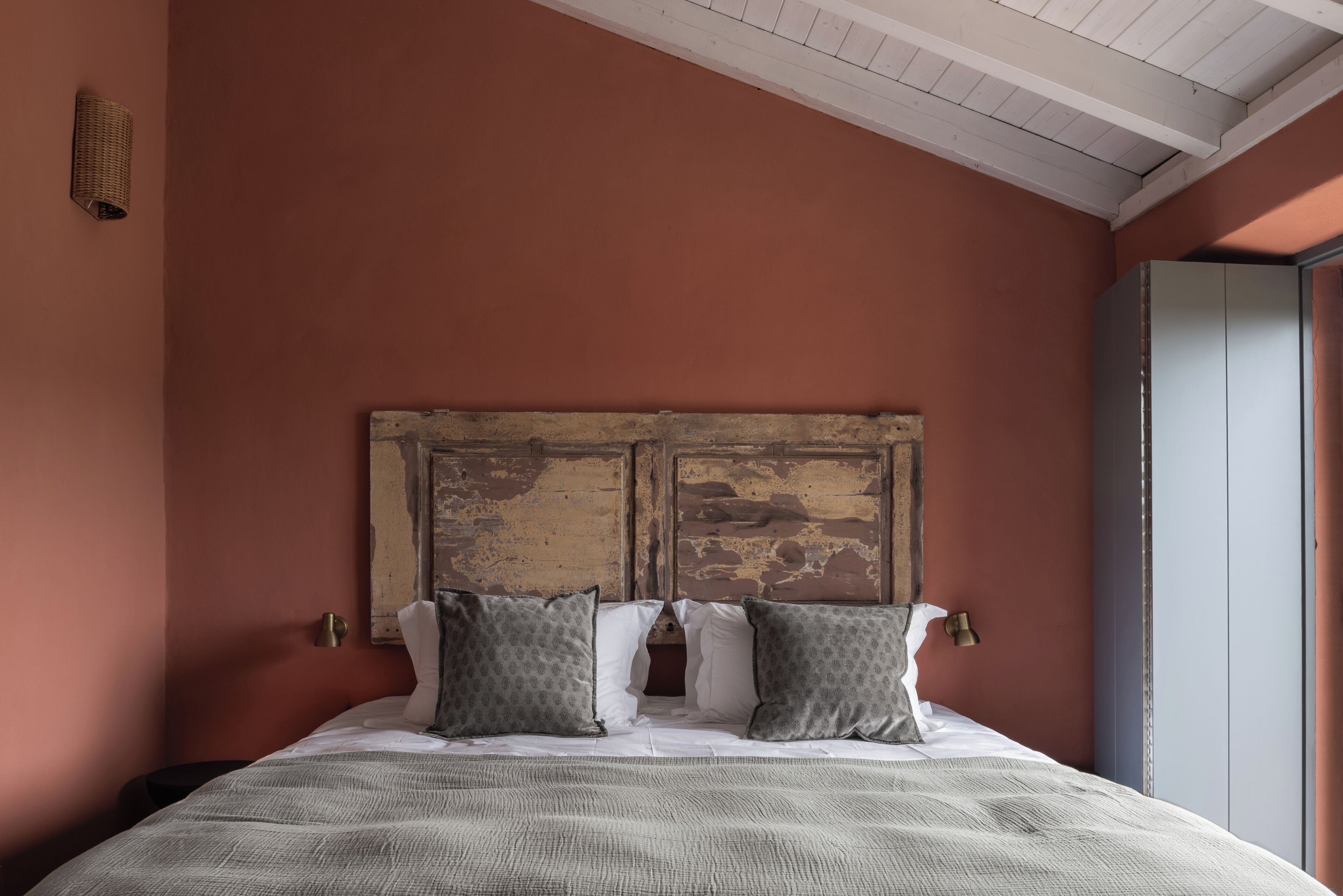A bed with a rustic headboard, two pillows, and a textured blanket.