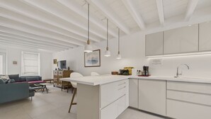 A modern kitchen with white cabinetry, pendant lights, and a dining area with a gray sofa and a small table. - Port and beaches within walking distance for 6 (Piriac-sur-Mer)