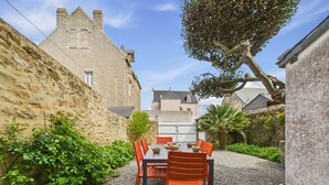 A courtyard with a table and chairs, surrounded by stone walls and greenery. - Port and beaches within walking distance for 6 (Piriac-sur-Mer)