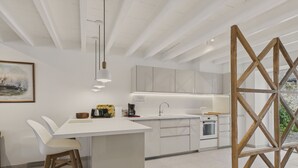 A modern kitchen with white cabinetry, a central island, and a wooden-framed window. - Port and beaches within walking distance for 6 (Piriac-sur-Mer)