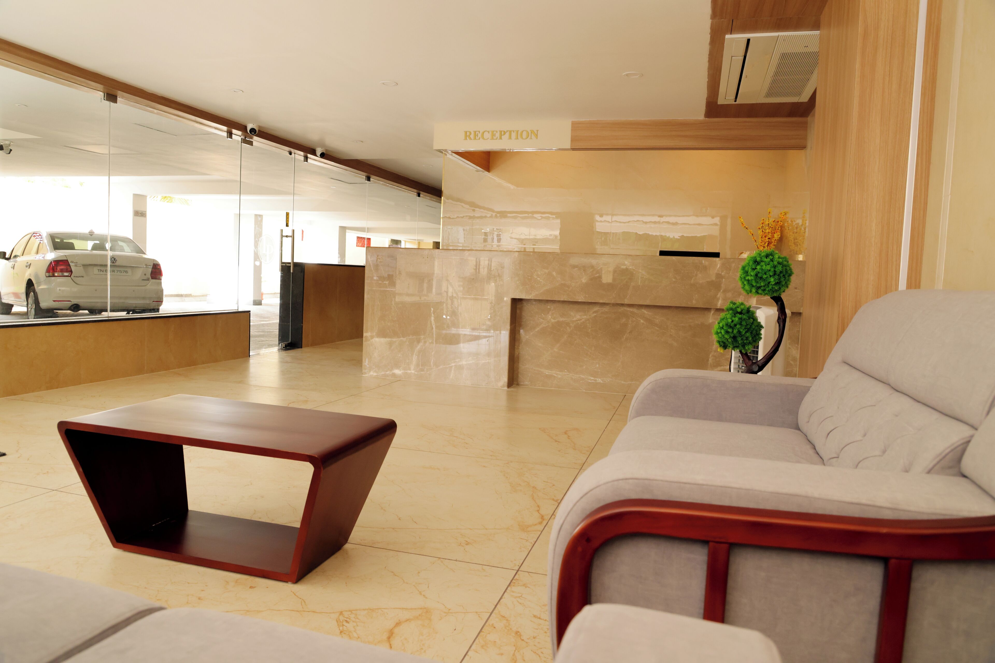 A reception area with a reception desk, a waiting area with a sofa and a coffee table, and a car in the background.