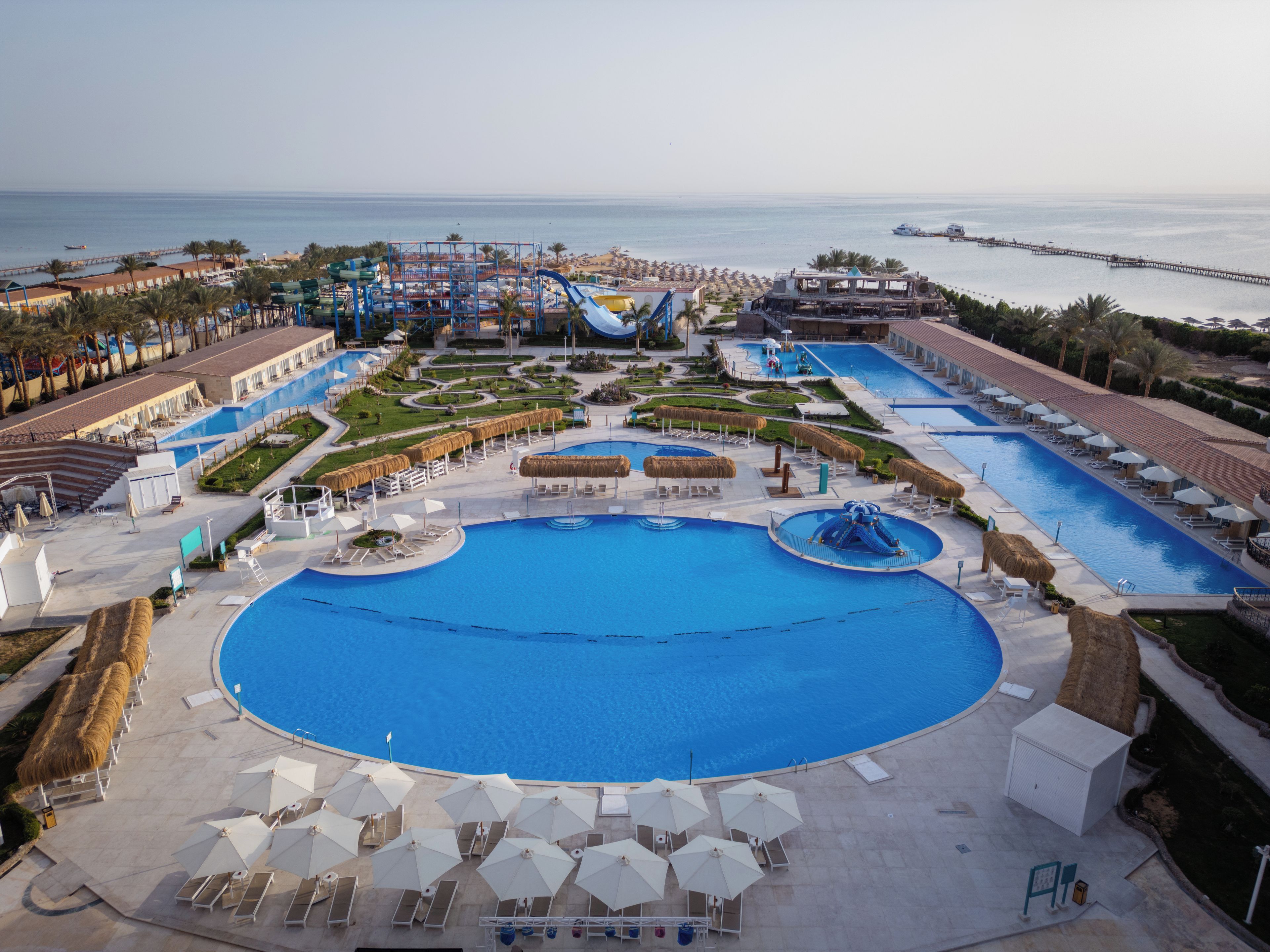 Un resort con una amplia piscina central, varias piscinas más pequeñas y un tobogán de agua.