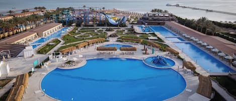 Un complexe hôtelier doté d’une grande piscine centrale, de plusieurs piscines plus petites et d’un toboggan aquatique.