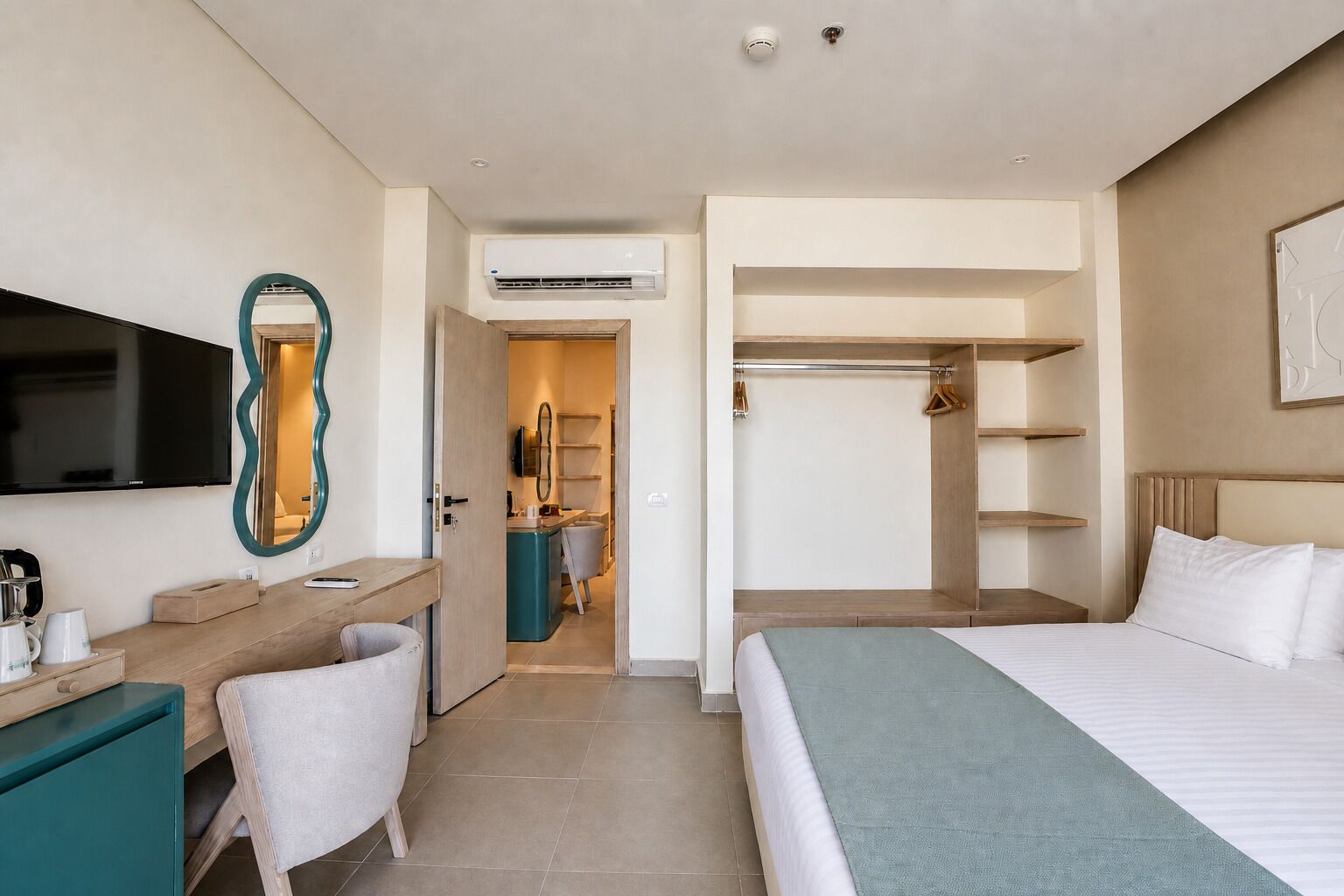 Une chambre d’hôtel équipée d’un lit, d’un bureau, d’une chaise, d’une télévision, d’une armoire et d’un appareil de climatisation.