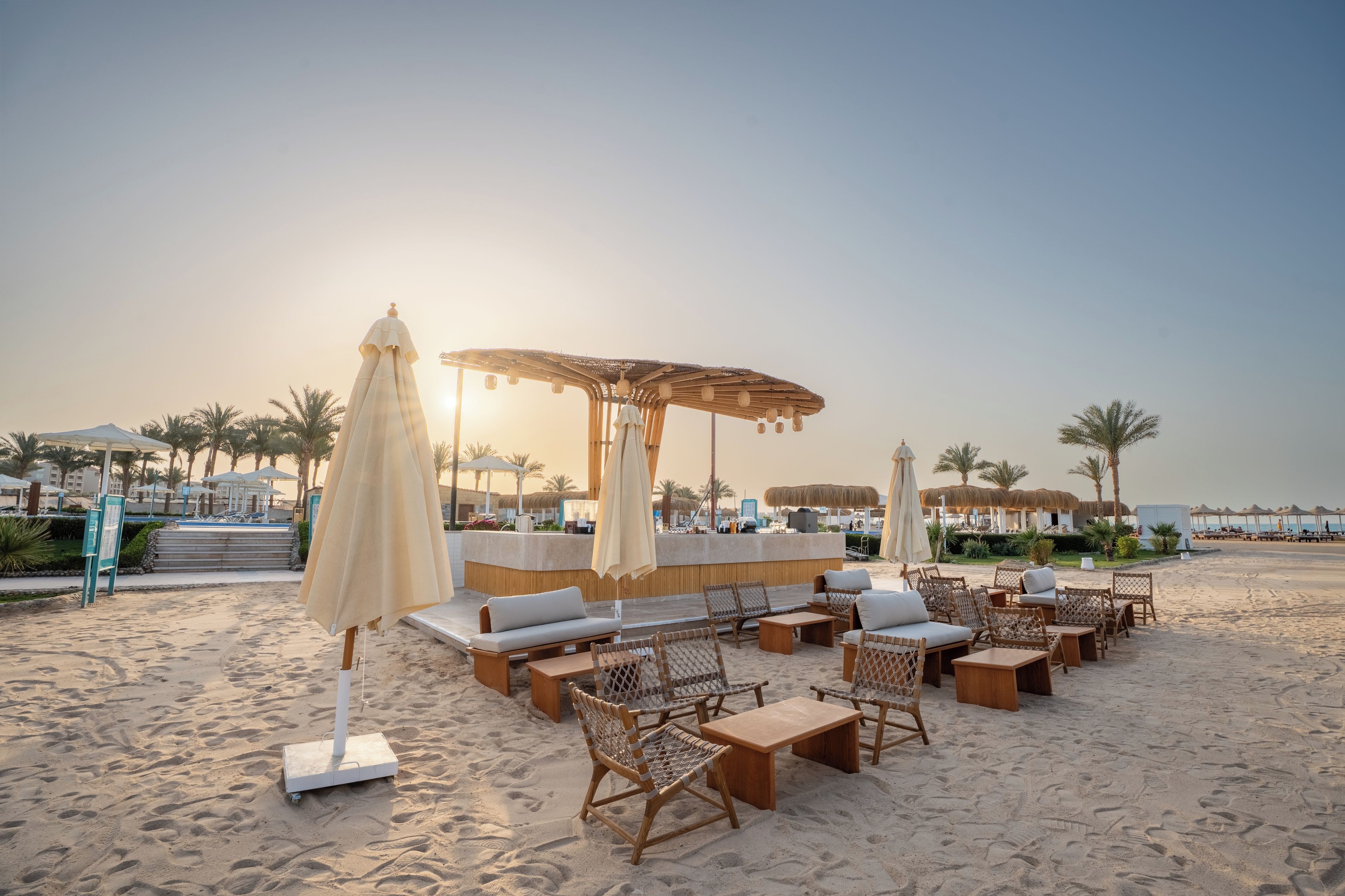 A beachside lounge area with sun loungers, a bar, and umbrellas.