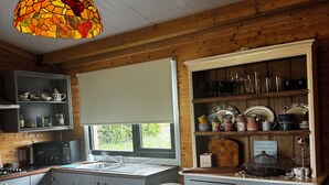 A cozy kitchen with wooden cabinets, a dining table, and a hanging stained glass light fixture.