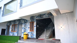Un bâtiment moderne avec un escalier menant à un étage supérieur, une poubelle et une pelouse bien entretenue.