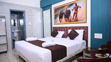 A hotel room with a large bed, a bathroom with a glass door, and a painting of a horse race on the wall.
