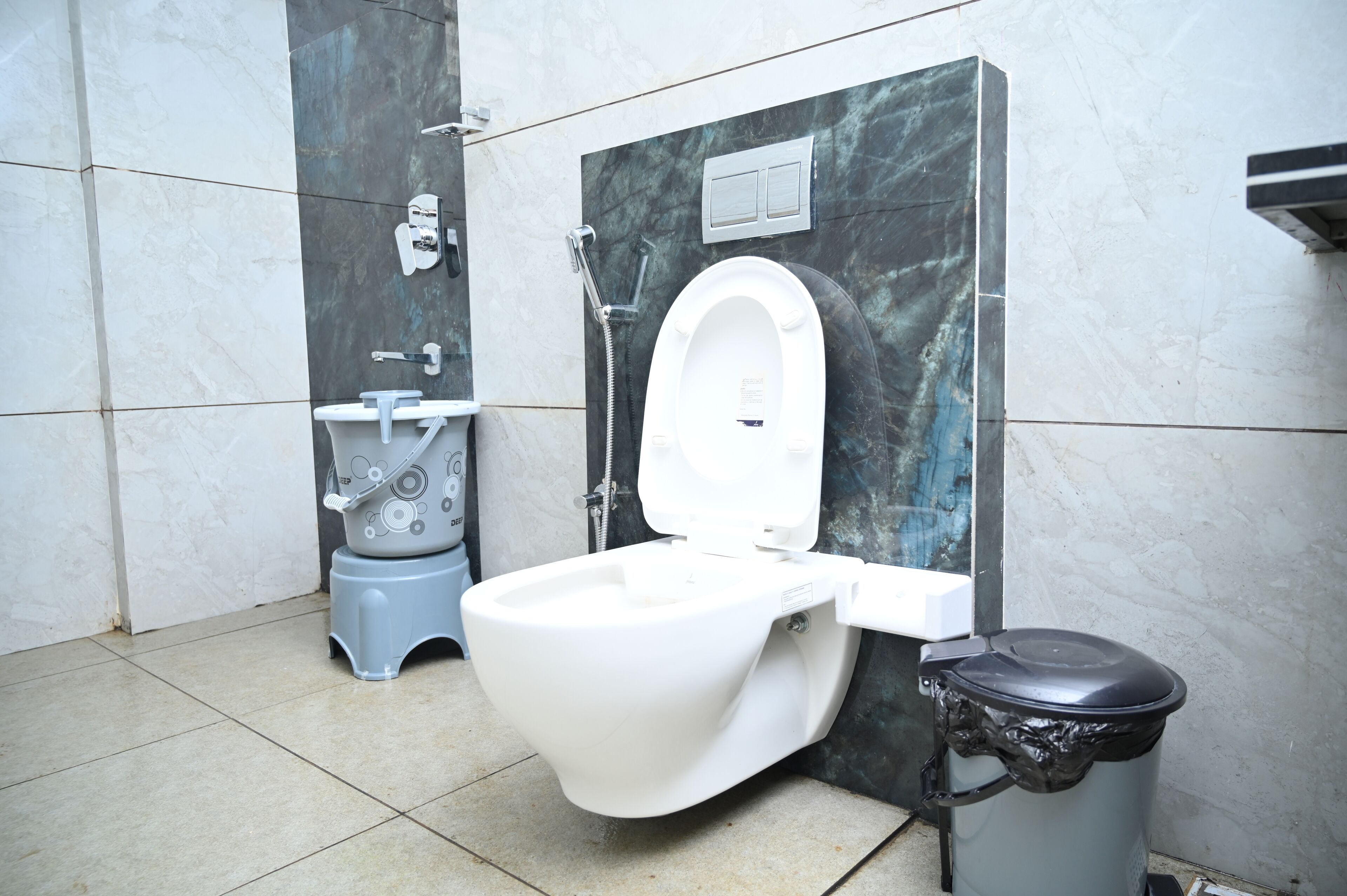 A modern bathroom with a white toilet, a bidet, and a trash bin.