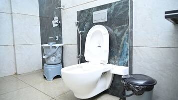 A modern bathroom with a white toilet, a bidet, and a trash bin.