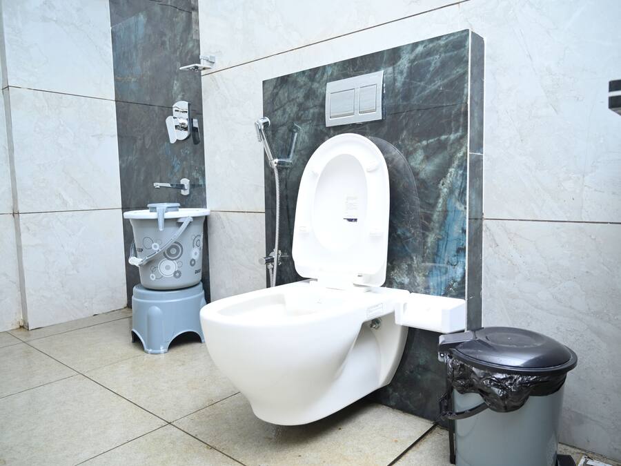 A modern bathroom with a white toilet, a bidet, and a trash bin.
